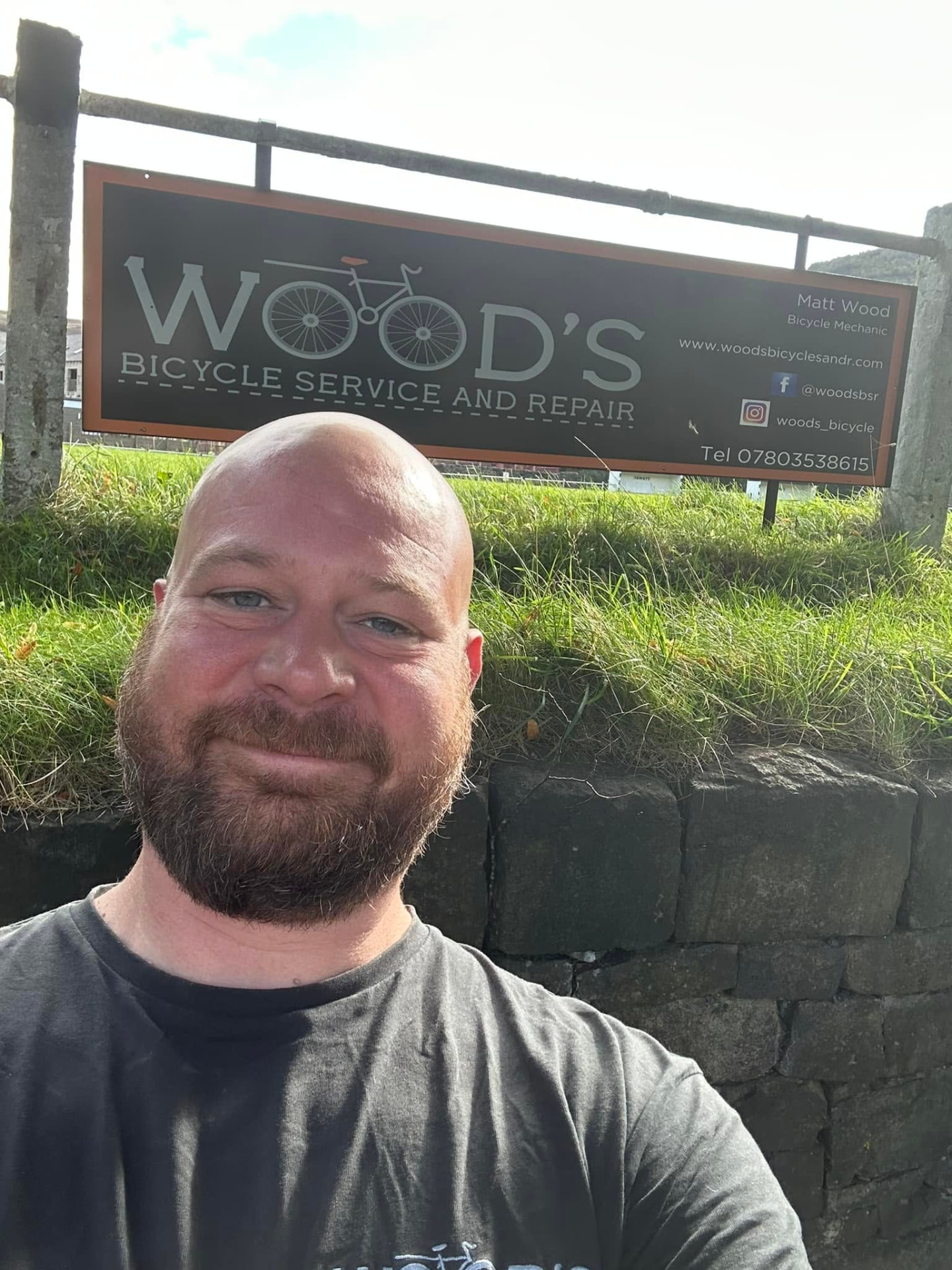 Matt Wood smiling in front of the Wood's Bicycle Service & Repair sign
